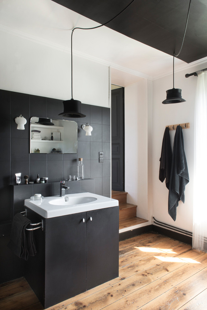 Idéer för mellanstora eklektiska vitt en-suite badrum, med svarta skåp, svart kakel, vita väggar, bänkskiva i akrylsten, släta luckor, mellanmörkt trägolv, ett konsol handfat och brunt golv