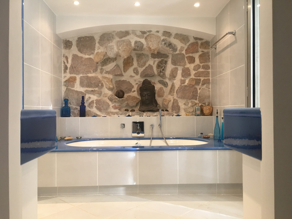 Пример оригинального дизайна: главная ванная комната в стиле кантри с полновстраиваемой ванной, серой плиткой, бежевым полом, плиткой из известняка, полом из керамогранита, подвесной раковиной, открытым душем, синей столешницей и тумбой под две раковины