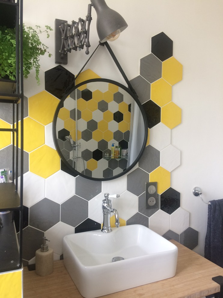 Medium sized retro ensuite bathroom with a claw-foot bath, a shower/bath combination, a wall mounted toilet, yellow tiles, ceramic tiles, yellow walls, bamboo flooring, a vessel sink and wooden worktops.