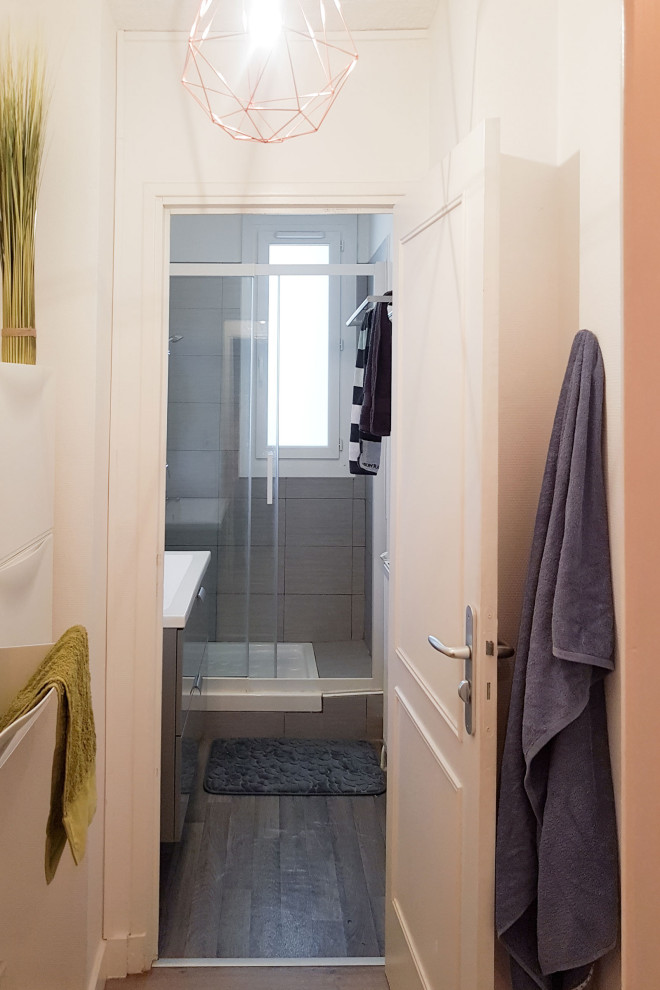 Idée de décoration pour une petite salle de bain design avec un placard avec porte à panneau surélevé, des portes de placard blanches, un carrelage gris, des carreaux de céramique, un mur blanc, un sol en vinyl, un lavabo encastré, un sol gris et une cabine de douche à porte coulissante.