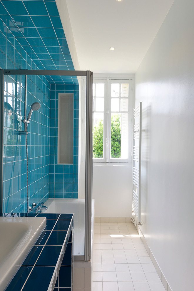 Modelo de cuarto de baño principal y largo y estrecho actual con bañera encastrada, combinación de ducha y bañera, baldosas y/o azulejos azules, paredes blancas, lavabo bajoencimera y encimera de azulejos