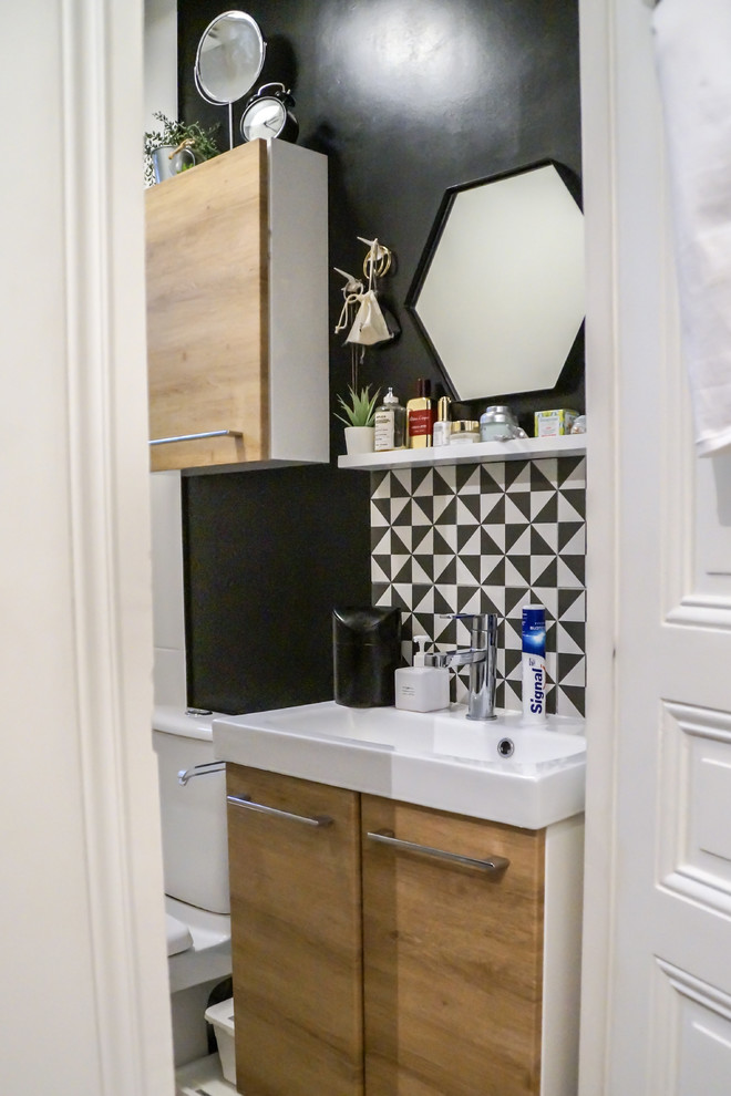 Idée de décoration pour une petite salle de bain nordique en bois clair avec un placard à porte affleurante, WC à poser, un carrelage noir et blanc, mosaïque, un mur noir, un lavabo encastré et un sol blanc.