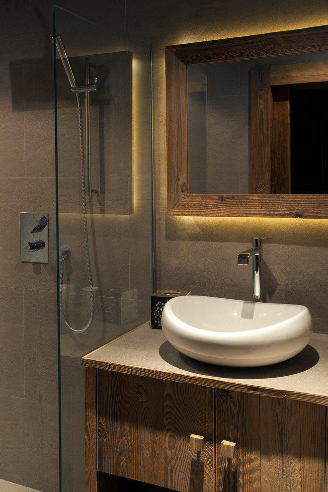 Cette image montre une salle de bain chalet en bois brun de taille moyenne avec une douche à l'italienne, un carrelage gris, des carreaux de céramique, un mur gris, un sol en carrelage de céramique, un lavabo posé et un plan de toilette en carrelage.