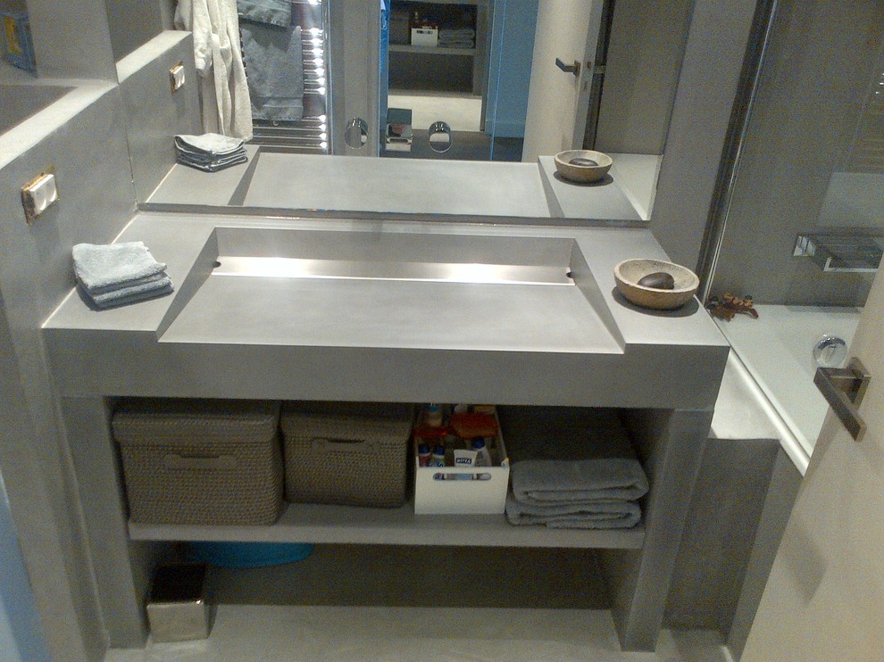 Ispirazione per un'ampia stanza da bagno padronale minimal con lavabo integrato, top in cemento, nessun'anta e ante grigie