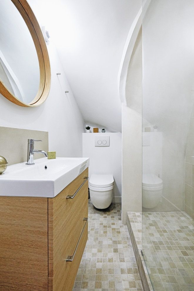 Inredning av ett medelhavsstil litet beige beige badrum med dusch, med släta luckor, skåp i ljust trä, en kantlös dusch, en vägghängd toalettstol, beige kakel, keramikplattor, vita väggar, mosaikgolv, ett avlångt handfat, laminatbänkskiva, grått golv och med dusch som är öppen