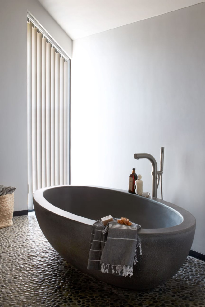 Idées déco pour une grande salle de bain contemporaine avec une baignoire indépendante, un mur blanc, un sol en galet et un sol gris.