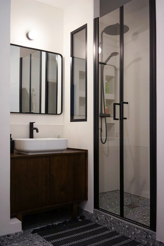Modern inredning av ett litet brun brunt badrum med dusch, med skåp i mörkt trä, en vägghängd toalettstol, vit kakel, keramikplattor, vita väggar, klinkergolv i keramik, träbänkskiva, grått golv, släta luckor, en dusch i en alkov, ett fristående handfat och dusch med gångjärnsdörr