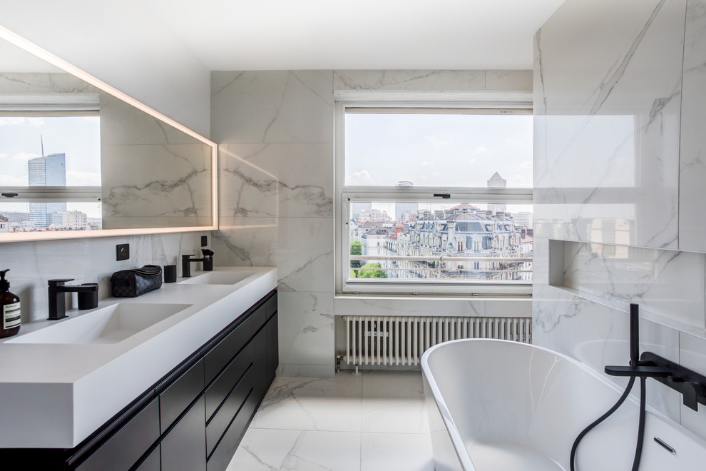Aménagement d'une salle de bain contemporaine avec une baignoire indépendante, un mur blanc, un lavabo intégré, un sol blanc et un plan de toilette blanc.