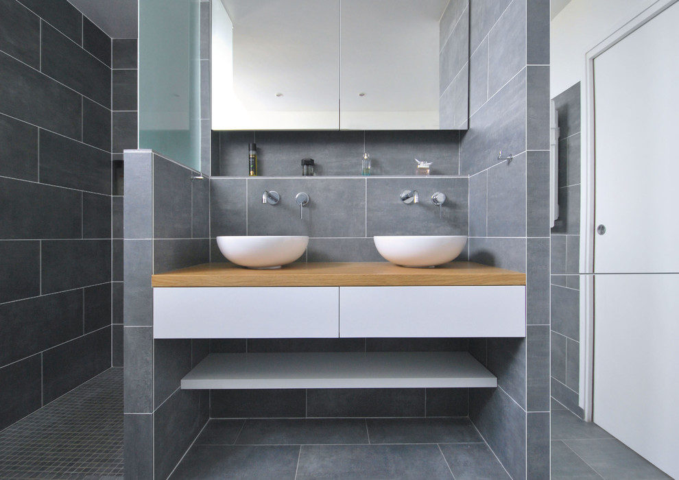 Large contemporary shower room bathroom in Paris with open cabinets, white cabinets, a built-in shower, grey tiles, a vessel sink, wooden worktops, an open shower and brown worktops.