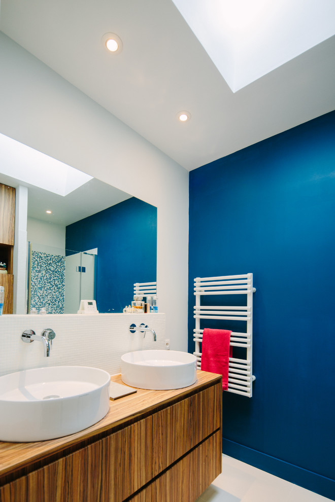 Источник вдохновения для домашнего уюта: ванная комната среднего размера в современном стиле с фасадами цвета дерева среднего тона, белой плиткой, синими стенами, душевой кабиной, настольной раковиной и столешницей из дерева