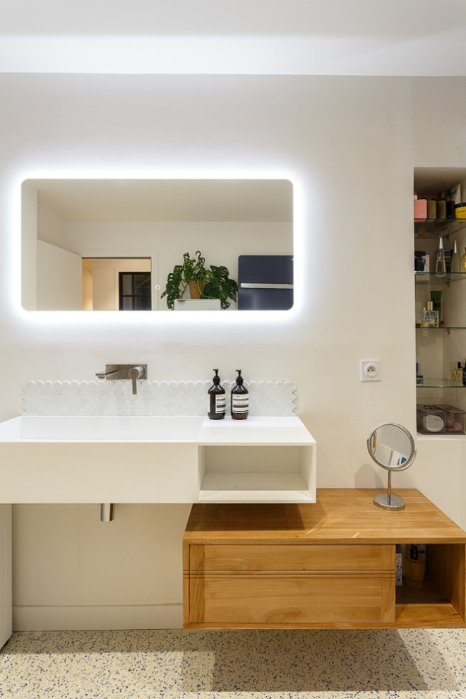 Inredning av ett modernt mellanstort vit vitt badrum med dusch, med släta luckor, vita skåp, vita väggar, terrazzogolv, ett avlångt handfat, bänkskiva i akrylsten och vitt golv