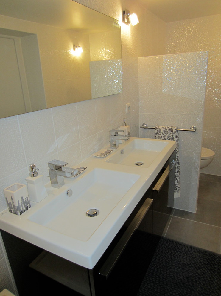 Inspiration för små moderna en-suite badrum, med luckor med profilerade fronter, svarta skåp, en kantlös dusch, en vägghängd toalettstol, vit kakel, keramikplattor, vita väggar, klinkergolv i keramik, ett konsol handfat, bänkskiva i akrylsten, grått golv och med dusch som är öppen