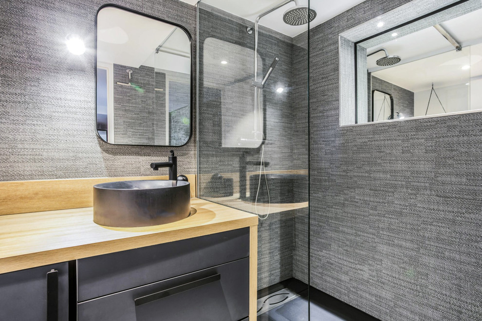 Inspiration for a mid-sized contemporary 3/4 gray tile and ceramic tile single-sink doorless shower remodel in Lyon with beaded inset cabinets, black cabinets, gray walls, a vessel sink, wood countertops, beige countertops and a freestanding vanity