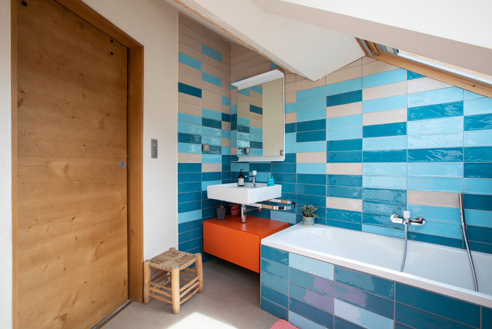 Пример оригинального дизайна: детская ванная комната среднего размера в современном стиле с плоскими фасадами, оранжевыми фасадами, полновстраиваемой ванной, инсталляцией, синей плиткой, керамической плиткой, полом из линолеума, консольной раковиной, столешницей из искусственного камня, серым полом, белой столешницей и синими стенами