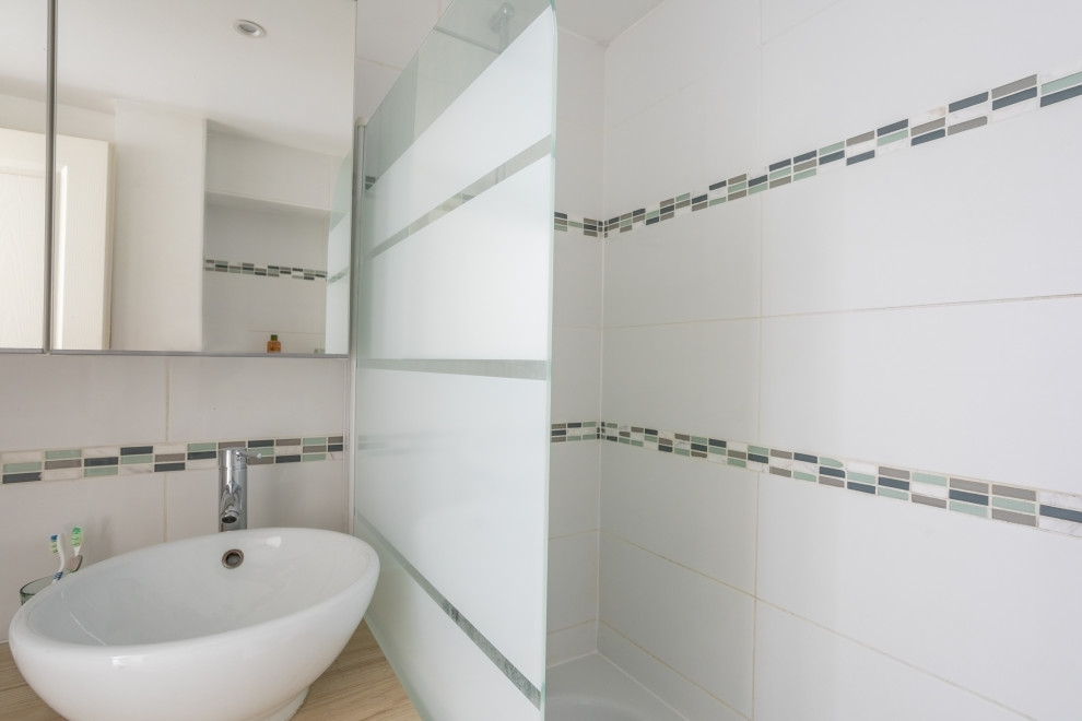 Exemple d'une petite salle de bain principale tendance avec des portes de placard blanches, une baignoire encastrée, un espace douche bain, un carrelage blanc, un carrelage en pâte de verre, un mur blanc, un sol en carrelage de céramique, un lavabo posé, un plan de toilette en stratifié, un sol gris et une cabine de douche à porte battante.