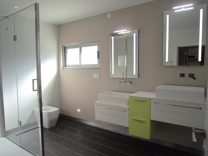 Idéer för ett modernt en-suite badrum, med ett väggmonterat handfat, gröna skåp, en kantlös dusch, svart kakel, beige väggar och dusch med gångjärnsdörr