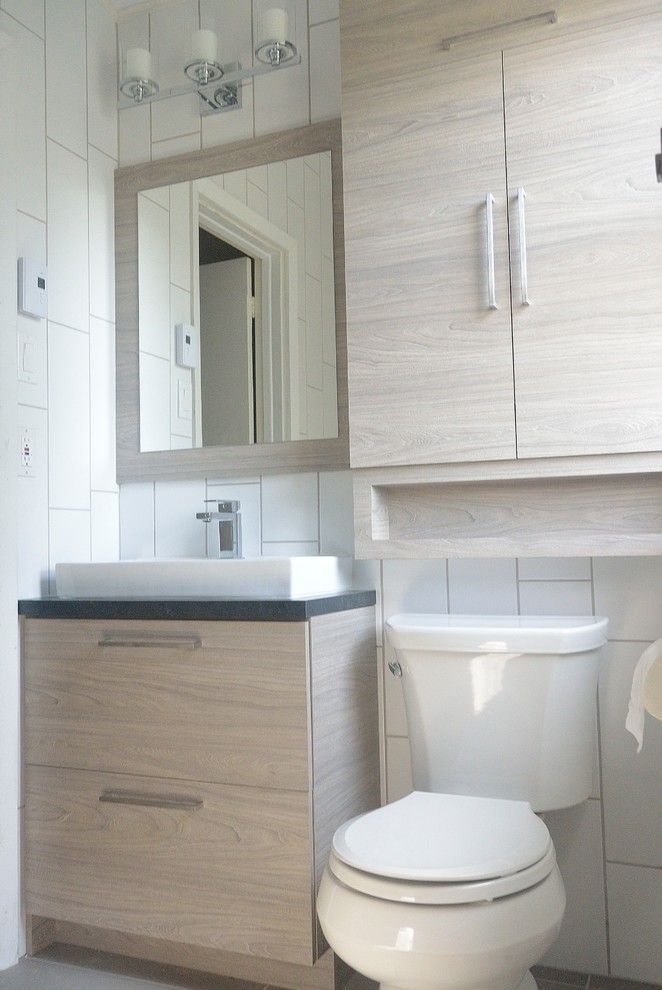 На фото: ванная комната в современном стиле с плоскими фасадами, душем над ванной, белой плиткой, керамогранитной плиткой, белыми стенами, полом из керамогранита, раковиной с несколькими смесителями и серым полом