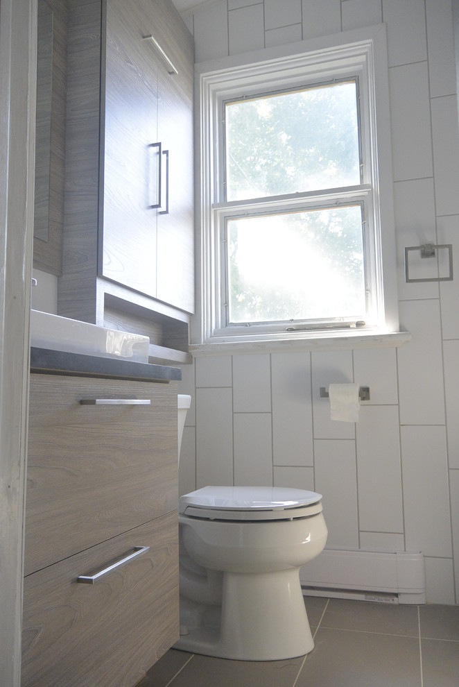 На фото: маленькая ванная комната в современном стиле с плоскими фасадами, белой плиткой, керамогранитной плиткой, белыми стенами, полом из керамогранита, раковиной с несколькими смесителями и серым полом для на участке и в саду