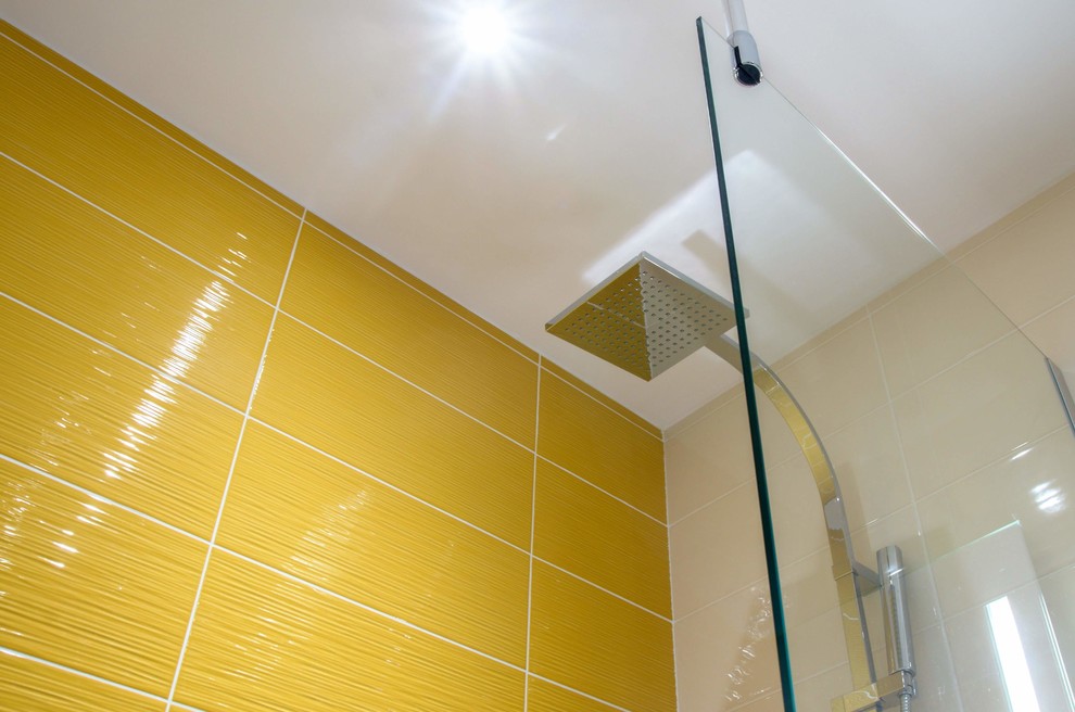 Exemple d'une salle d'eau tendance de taille moyenne avec une douche ouverte, WC suspendus, un carrelage jaune, des carreaux de céramique, un mur jaune, un sol en carrelage de céramique, un lavabo suspendu, un sol gris, aucune cabine et un plan de toilette blanc.