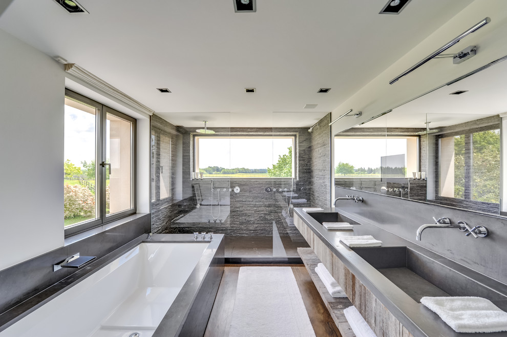 Пример оригинального дизайна: главная ванная комната среднего размера в современном стиле с открытыми фасадами, искусственно-состаренными фасадами, полновстраиваемой ванной, каменной плиткой, белыми стенами, паркетным полом среднего тона, монолитной раковиной, столешницей из бетона, двойным душем и открытым душем