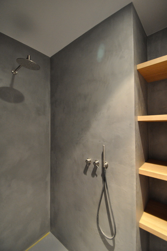 Modern inredning av ett badrum, med en kantlös dusch, beige väggar, betonggolv, ett avlångt handfat, grått golv och dusch med gångjärnsdörr