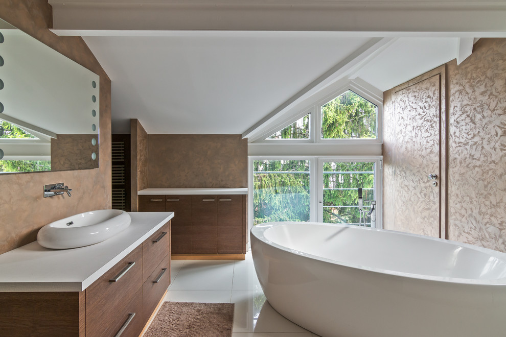 Aménagement d'une salle de bain contemporaine en bois brun avec un placard à porte plane, une baignoire indépendante, un mur beige, une vasque et un sol blanc.