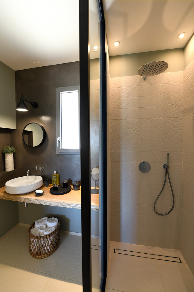 Cette image montre une petite salle d'eau méditerranéenne avec une douche à l'italienne, un carrelage beige, des carreaux de céramique, un lavabo posé et un plan de toilette en bois.