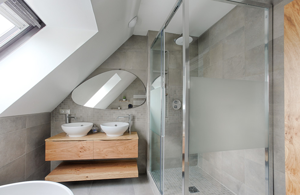 Idée de décoration pour une grande salle de bain minimaliste en bois clair avec un placard à porte plane, une douche à l'italienne, un carrelage gris, un mur gris, un lavabo posé, un plan de toilette en bois, un sol gris, une cabine de douche à porte coulissante et un plan de toilette marron.