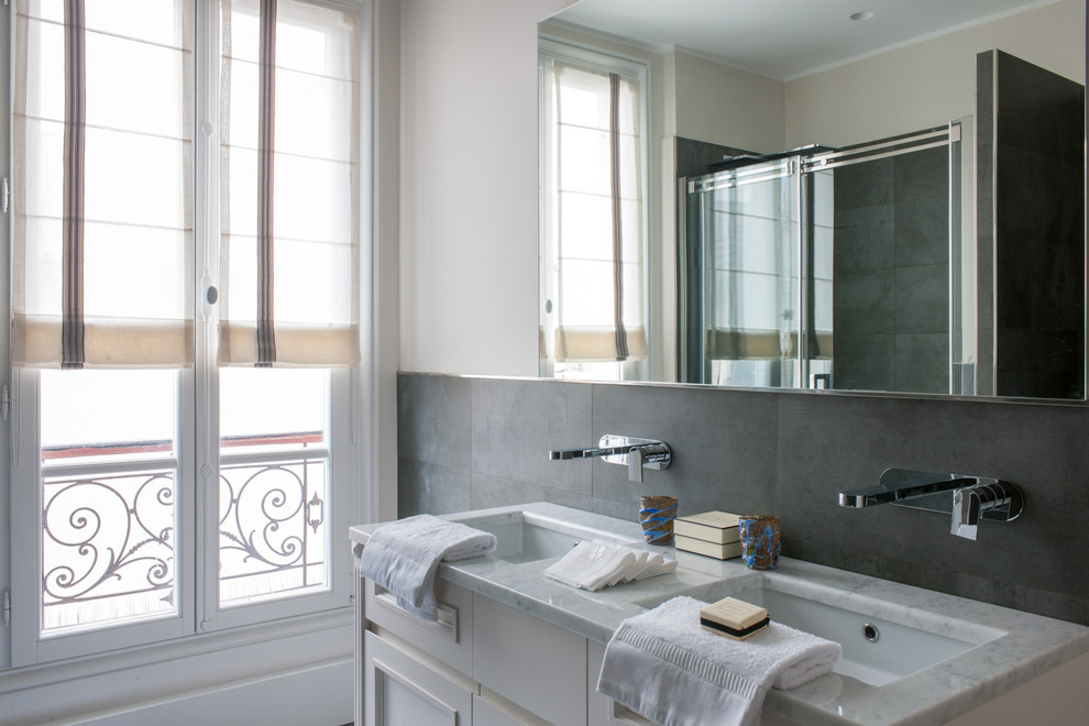 Immagine di una stanza da bagno con doccia tradizionale di medie dimensioni con ante bianche, doccia alcova, piastrelle grigie, pareti bianche, lavabo integrato e top in marmo