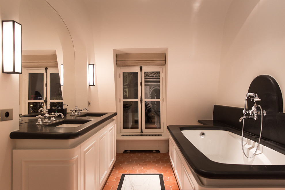 Идея дизайна: большая ванная комната в стиле неоклассика (современная классика) с полновстраиваемой ванной, душем без бортиков, мраморной плиткой, белыми стенами, кирпичным полом, врезной раковиной, столешницей из гранита, душем с распашными дверями и черной столешницей