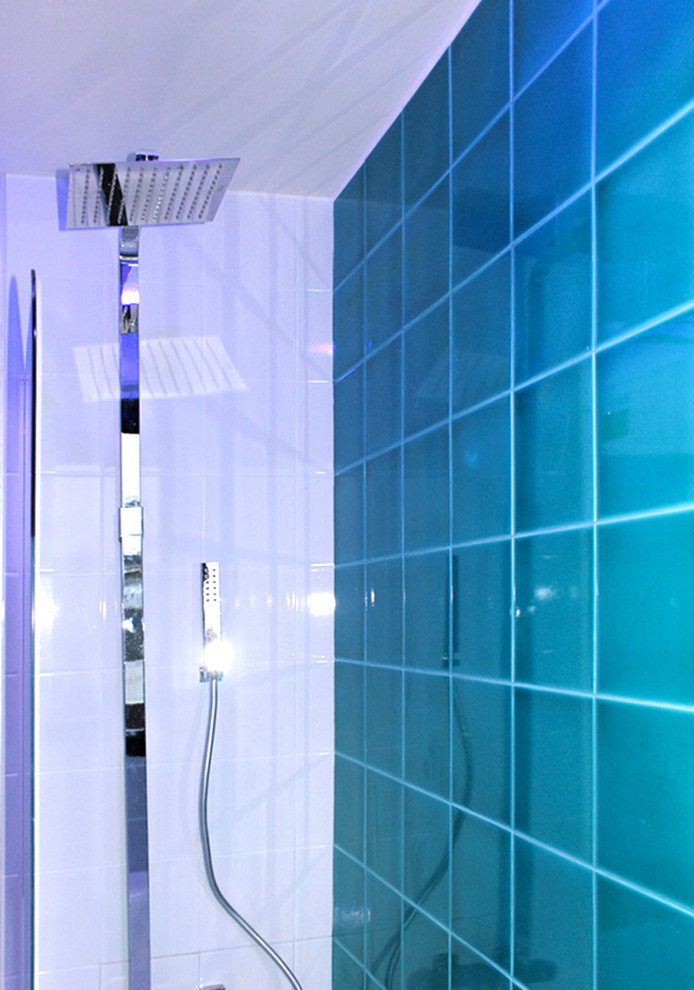Réalisation d'une salle de bain design avec un combiné douche/baignoire, un carrelage bleu et un mur bleu.