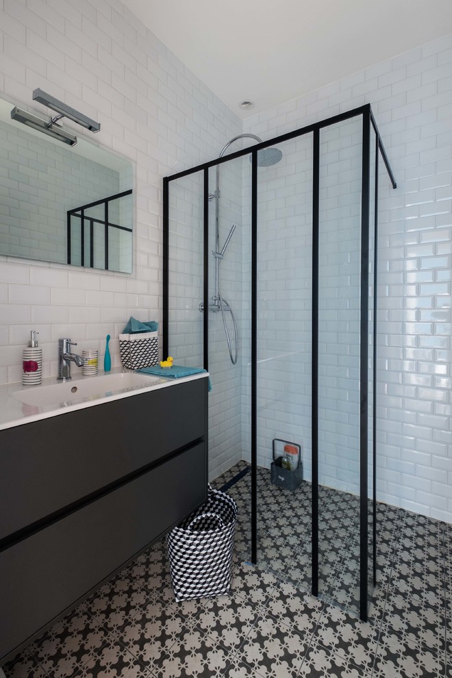 На фото: ванная комната среднего размера в стиле лофт с черными фасадами, душем без бортиков, белыми стенами, душевой кабиной, монолитной раковиной, плиткой кабанчик и черно-белой плиткой с