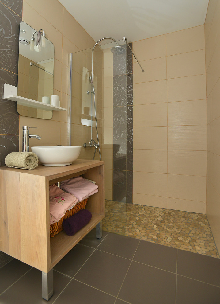 Foto på ett funkis badrum med dusch, med öppna hyllor, en kantlös dusch, brun kakel, grå väggar, ett fristående handfat, träbänkskiva och med dusch som är öppen