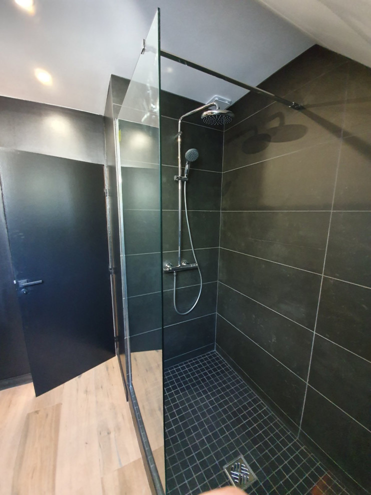 Inspiration för ett mellanstort funkis svart svart en-suite badrum, med en kantlös dusch, en vägghängd toalettstol, svart kakel, porslinskakel, svarta väggar, ett väggmonterat handfat, träbänkskiva, beiget golv och med dusch som är öppen
