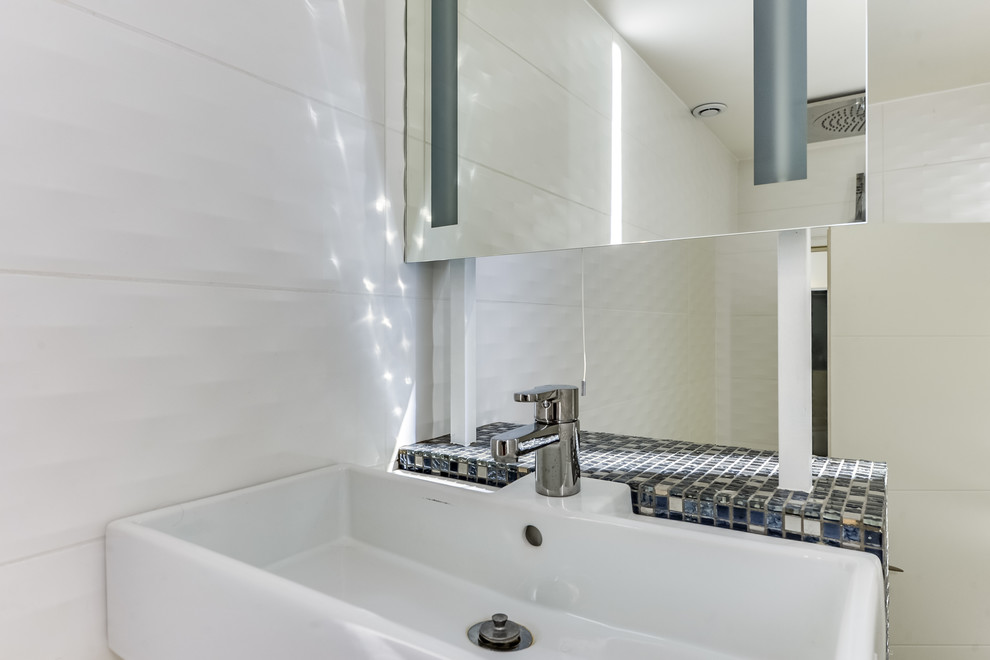 Cette image montre une petite salle d'eau design avec une douche à l'italienne, WC suspendus, un carrelage blanc, des carreaux de céramique, un mur blanc, un sol en carrelage de céramique, une grande vasque, un sol gris et aucune cabine.