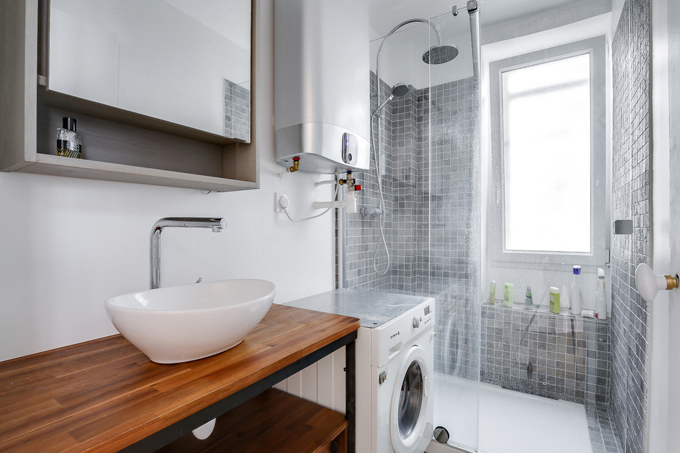 Mittelgroßes Modernes Duschbad mit grauen Fliesen, weißer Wandfarbe, Schieferboden, Einbauwaschbecken, Waschtisch aus Holz, schwarzem Boden, Falttür-Duschabtrennung und brauner Waschtischplatte in Paris