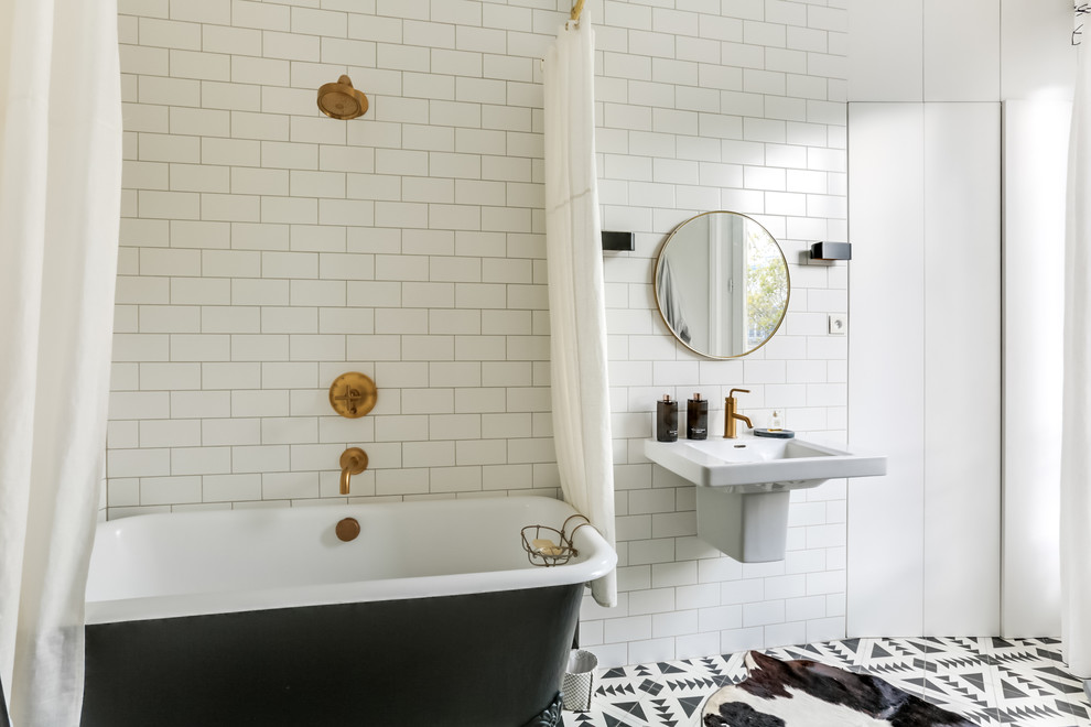 Inredning av ett klassiskt en-suite badrum, med släta luckor, vita skåp, ett badkar med tassar, en dusch/badkar-kombination, svart och vit kakel, vita väggar, ett väggmonterat handfat, cementgolv och dusch med duschdraperi