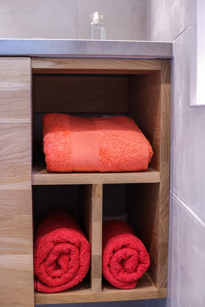 Inspiration for a small contemporary shower room bathroom in Paris with beaded cabinets, light wood cabinets, a wall mounted toilet, grey tiles, porcelain tiles, grey walls, porcelain flooring, a submerged sink, limestone worktops, grey floors, a hinged door and a corner shower.