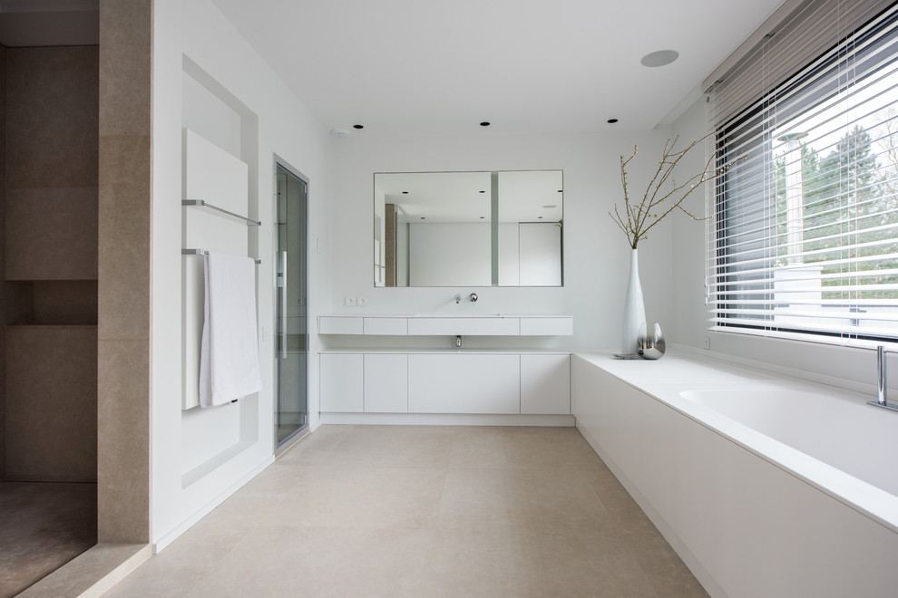Inredning av ett modernt stort en-suite badrum, med vita skåp, ett undermonterat badkar, en dusch i en alkov, beige kakel, keramikplattor, vita väggar, ett integrerad handfat och dusch med gångjärnsdörr