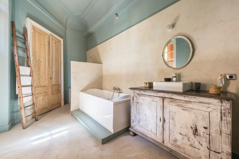 Exemple d'une salle de bain éclectique en bois vieilli avec une baignoire posée, un mur bleu, une vasque et un placard avec porte à panneau encastré.