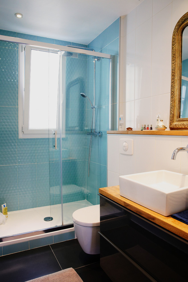 Cette image montre une petite salle de bain bohème avec un lavabo posé, un plan de toilette en bois, WC suspendus, un carrelage gris, des carreaux de céramique et un mur blanc.
