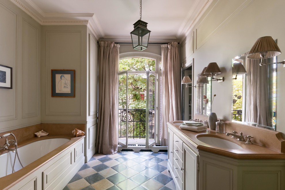 Exemple d'une salle de bain principale chic avec un placard avec porte à panneau encastré, des portes de placard grises, une baignoire encastrée, un mur gris, un lavabo encastré, un sol multicolore et un plan de toilette beige.
