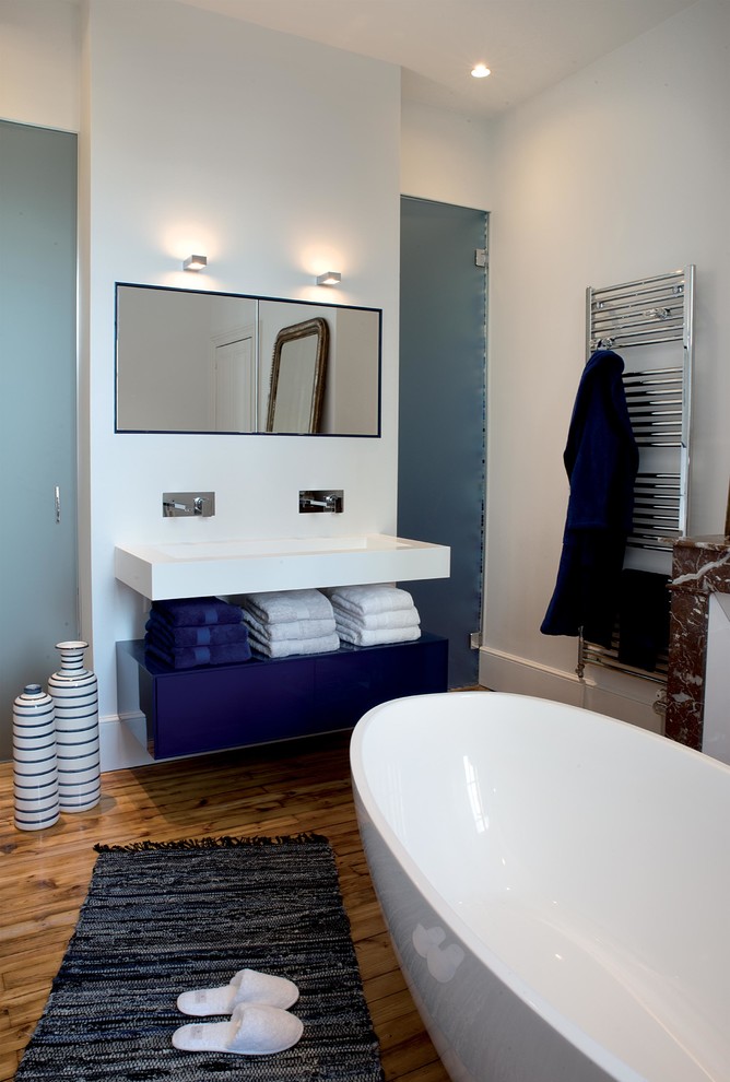 Mittelgroßes Modernes Badezimmer En Suite mit offenen Schränken, blauen Schränken, freistehender Badewanne, weißer Wandfarbe, braunem Holzboden und integriertem Waschbecken in Clermont-Ferrand