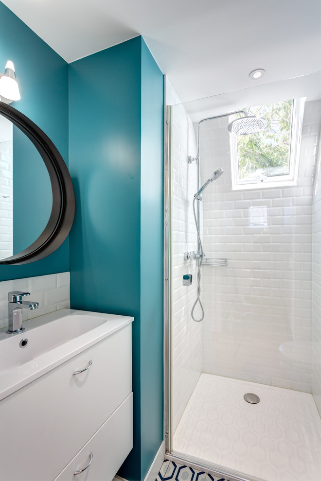 Пример оригинального дизайна: маленькая главная ванная комната в стиле модернизм с плоскими фасадами, белыми фасадами, душем без бортиков, раздельным унитазом, белой плиткой, плиткой кабанчик, синими стенами, полом из цементной плитки, консольной раковиной, столешницей из искусственного камня, синим полом, душем с распашными дверями и белой столешницей для на участке и в саду