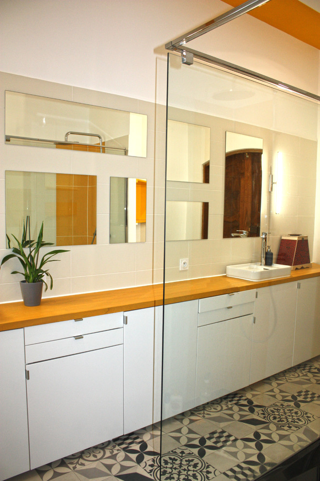 Aménagement d'une salle de bain principale contemporaine de taille moyenne avec un placard à porte affleurante, des portes de placard jaunes, une douche ouverte, un carrelage gris, des carreaux de céramique, un mur jaune, un sol en linoléum, une vasque et un plan de toilette en bois.