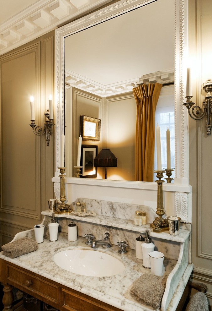 パリにある高級な広いヴィクトリアン調のおしゃれなマスターバスルーム (中間色木目調キャビネット、ベージュの壁、アンダーカウンター洗面器、大理石の洗面台) の写真