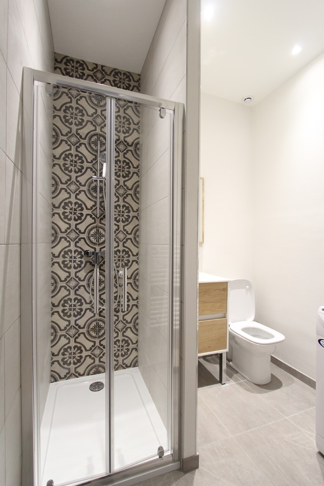 Cette image montre une petite salle de bain principale design avec une douche ouverte, WC à poser, un carrelage gris, des carreaux de céramique, un mur gris, un sol en carrelage de céramique, un plan vasque, un sol gris et une cabine de douche à porte battante.