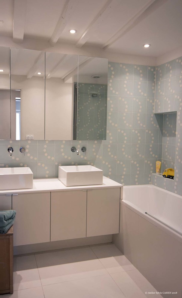 Пример оригинального дизайна: детская ванная комната среднего размера в современном стиле с плоскими фасадами, белыми фасадами, полновстраиваемой ванной, инсталляцией, синей плиткой, керамической плиткой, синими стенами, полом из керамической плитки, накладной раковиной, столешницей из искусственного кварца, белым полом, белой столешницей, нишей, тумбой под две раковины, подвесной тумбой и деревянным потолком