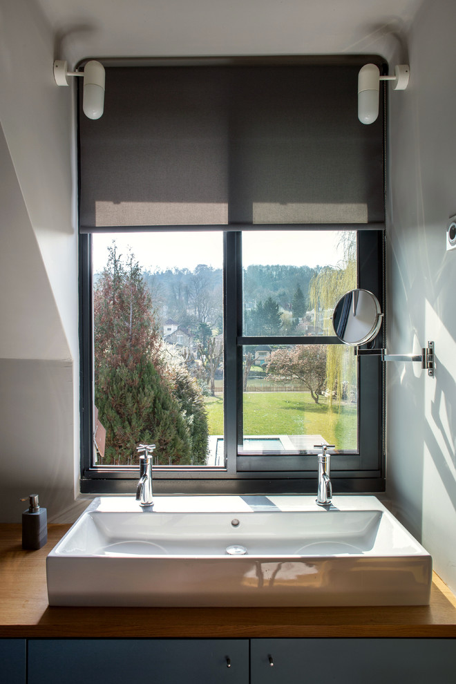 Cette photo montre une petite salle de bain principale et blanche et bois moderne avec des portes de placard grises, un mur gris, un lavabo encastré, un plan de toilette marron, une fenêtre et meuble simple vasque.