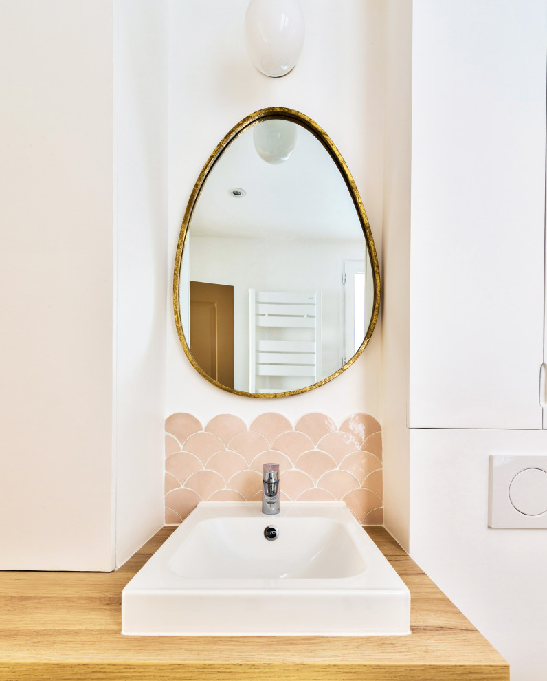Идея дизайна: маленькая ванная комната в скандинавском стиле с плоскими фасадами, белыми фасадами, душем без бортиков, инсталляцией, розовой плиткой, белыми стенами, душевой кабиной, консольной раковиной, столешницей из дерева, бежевым полом, открытым душем, тумбой под одну раковину и встроенной тумбой для на участке и в саду